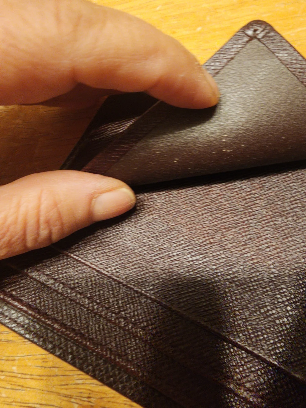burgandy Louis Vuitton Taiga leather bifold wallet featuring a debossed LV